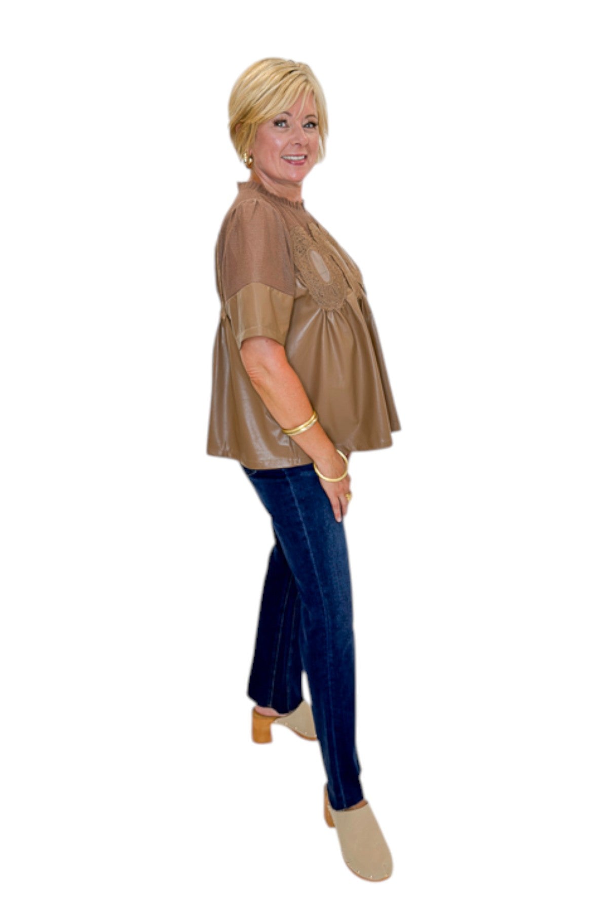 Side view of woman wearing Swagger Boutique’s Mocha Lace Applique Faux Leather Top with jeans against white studio background.