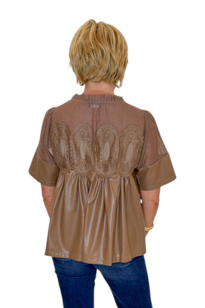 Back view of woman wearing Swagger Boutique’s Mocha Lace Applique Faux Leather Top with jeans against white studio background.