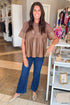 Front view of woman wearing Swagger Boutique’s Mocha Lace Applique Faux Leather Top with jeans standing at the store.