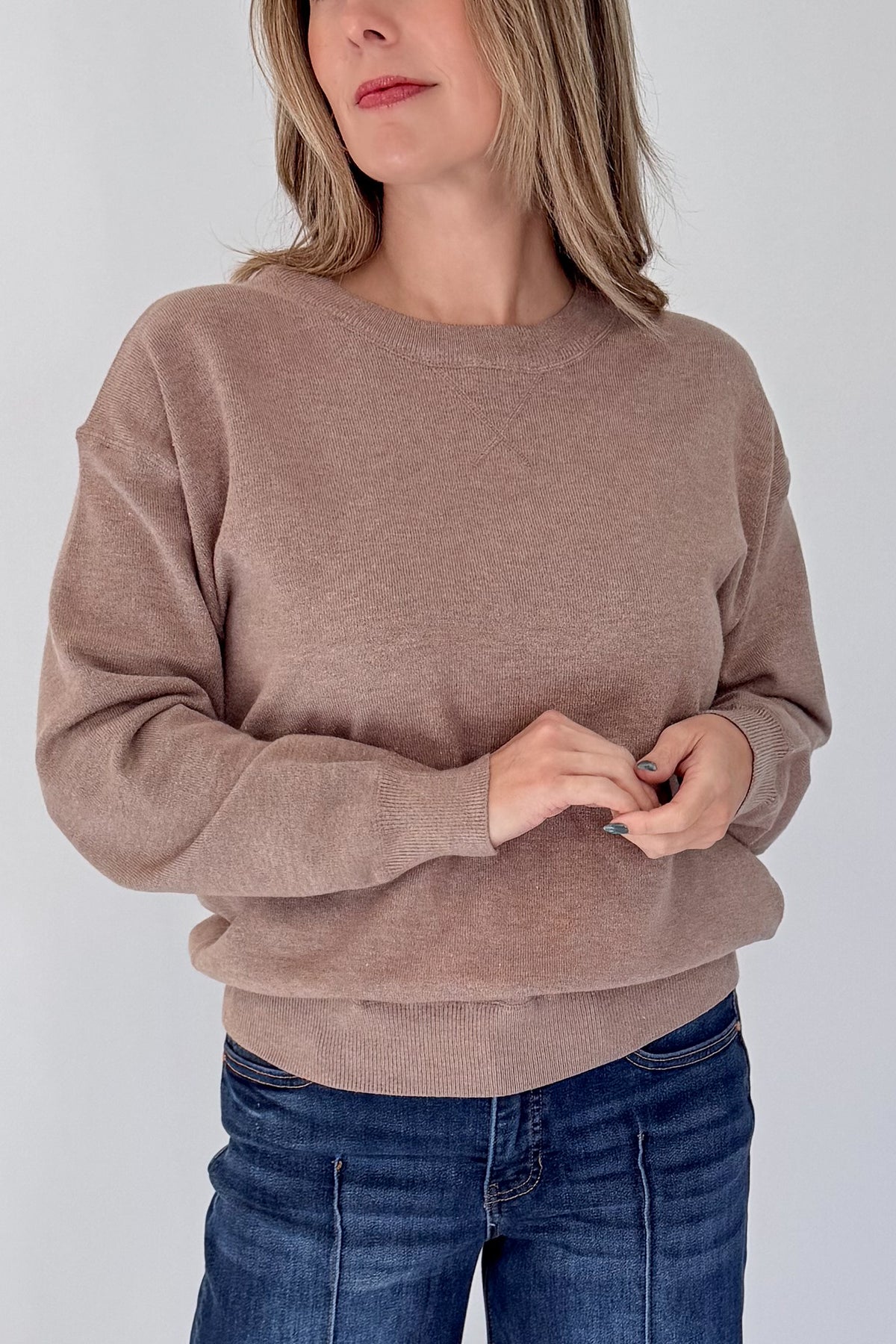 Front detail view of woman wearing Swagger Boutique’s Mocha Ribbed Hem Sweatshirt with jeans against white studio background.