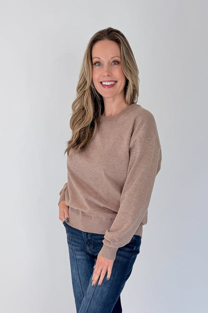 Side view of woman wearing Swagger Boutique’s Mocha Ribbed Hem Sweatshirt with jeans against white studio background.