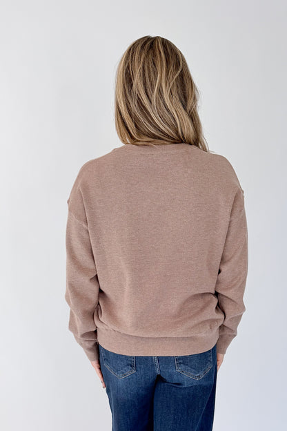 Back view of woman wearing Swagger Boutique’s Mocha Ribbed Hem Sweatshirt with jeans against white studio background.