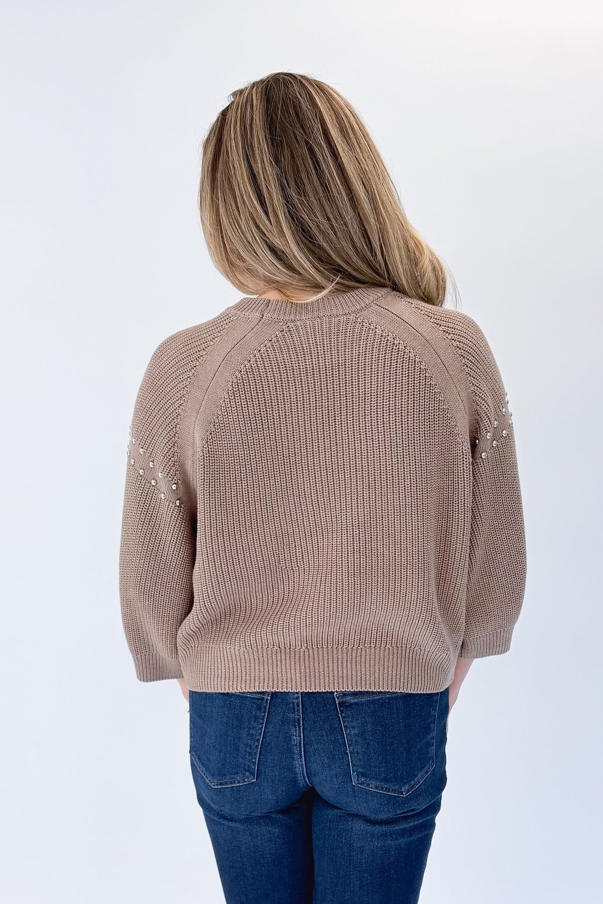 Back view of woman wearing Swagger Boutique’s Mocha Stud Detail Sweater by Entro with jeans against white studio background.