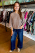 Front view of woman wearing Swagger Boutique’s Mocha Stud Detail Sweater by Entro with jeans standing at the store.