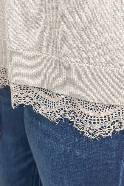 Front detail view of woman wearing Swagger Boutique’s Mocha Lace Lined V-Neck Sweater  with jeans with clothing hanging in the background.