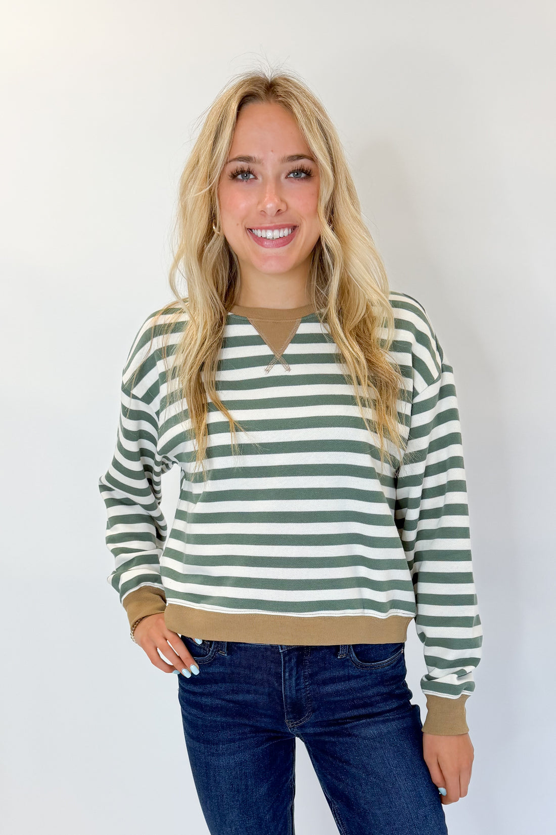Front view of woman wearing Swagger Boutique’s Monstera Low Key Stripe Sweatshirt by Z Supply with jeans against white studio background.