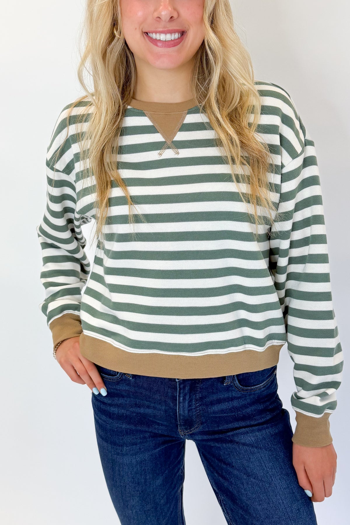Front detail view of woman wearing Swagger Boutique’s Monstera Low Key Stripe Sweatshirt by Z Supply with jeans against white studio background.