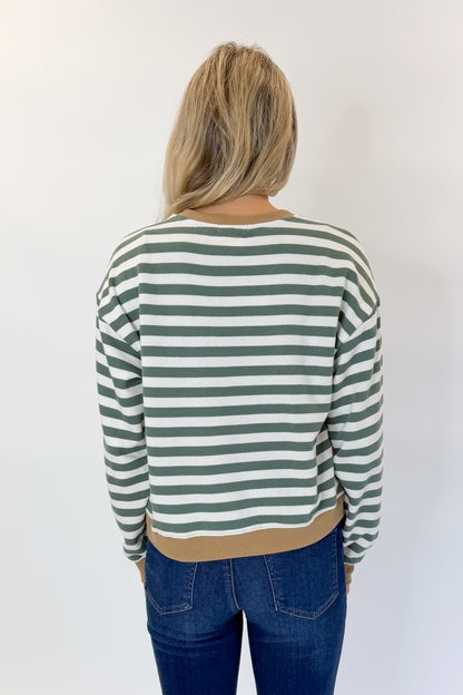 Back view of woman wearing Swagger Boutique’s Monstera Low Key Stripe Sweatshirt by Z Supply with jeans against white studio background.