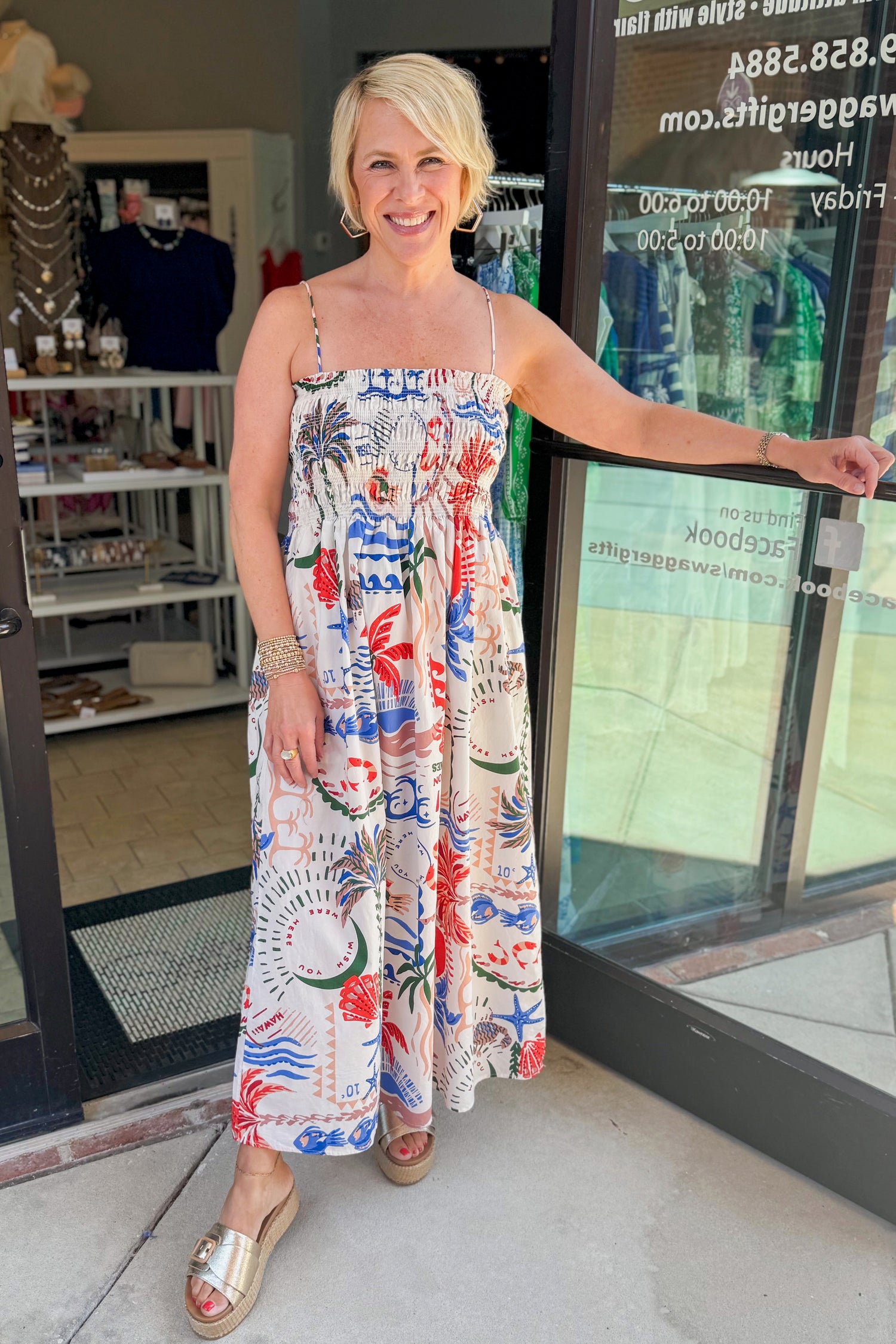 Front view of woman wearing Swagger Boutique’s Multi Cornelia Getaway Dress by Z Supply with sandals standing outside the store.