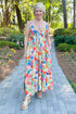 Front view of woman wearing Swagger Boutique’s Multi Floral Midi Dress walking outside on a path.