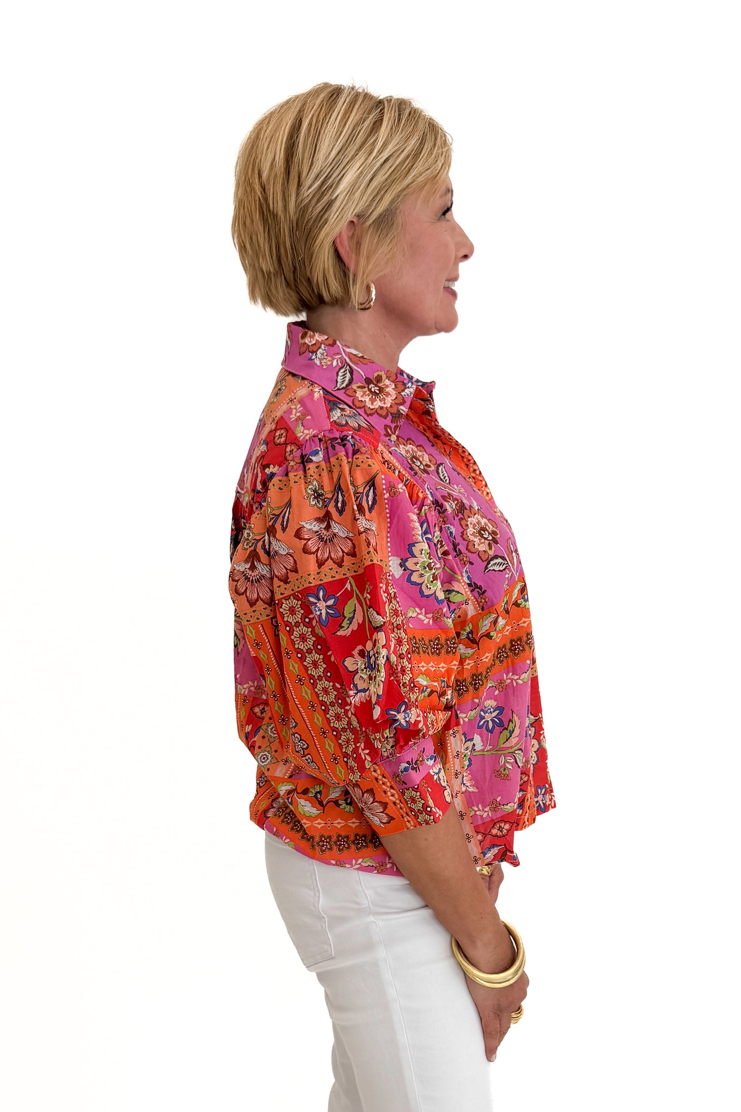 Side view of woman wearing Swagger Boutique’s Multi Floral Patchwork Top with jeans against white studio background.