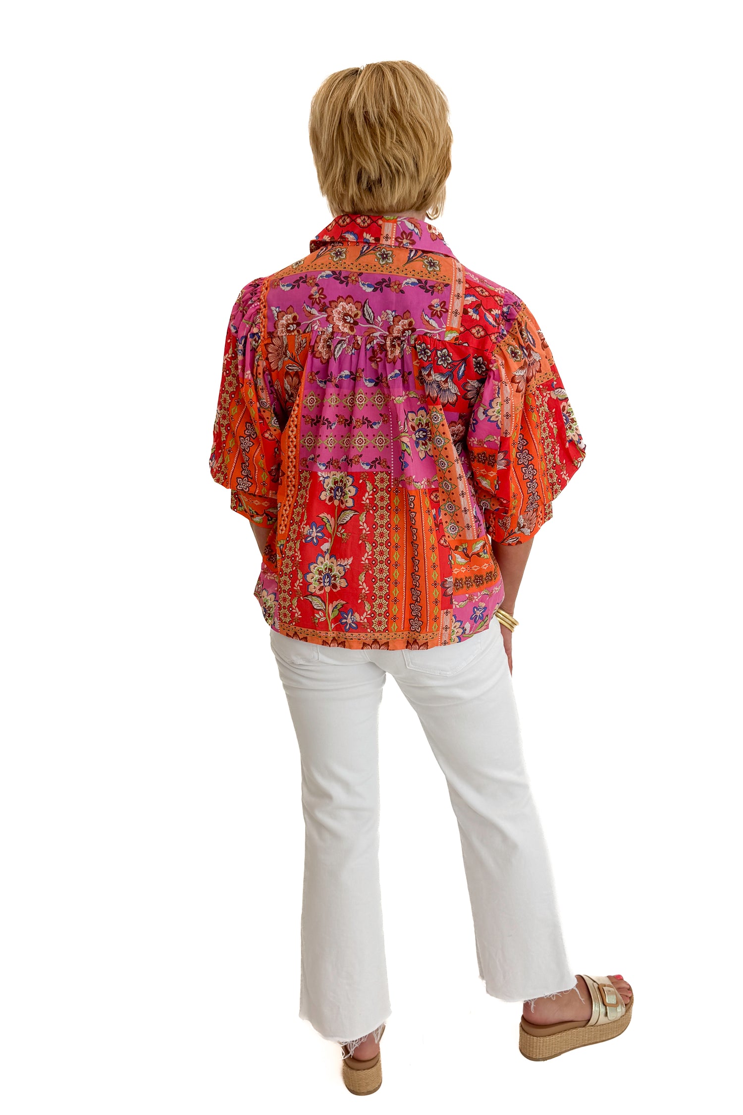 Back view of woman wearing Swagger Boutique’s Multi Floral Patchwork Top with jeans against white studio background.