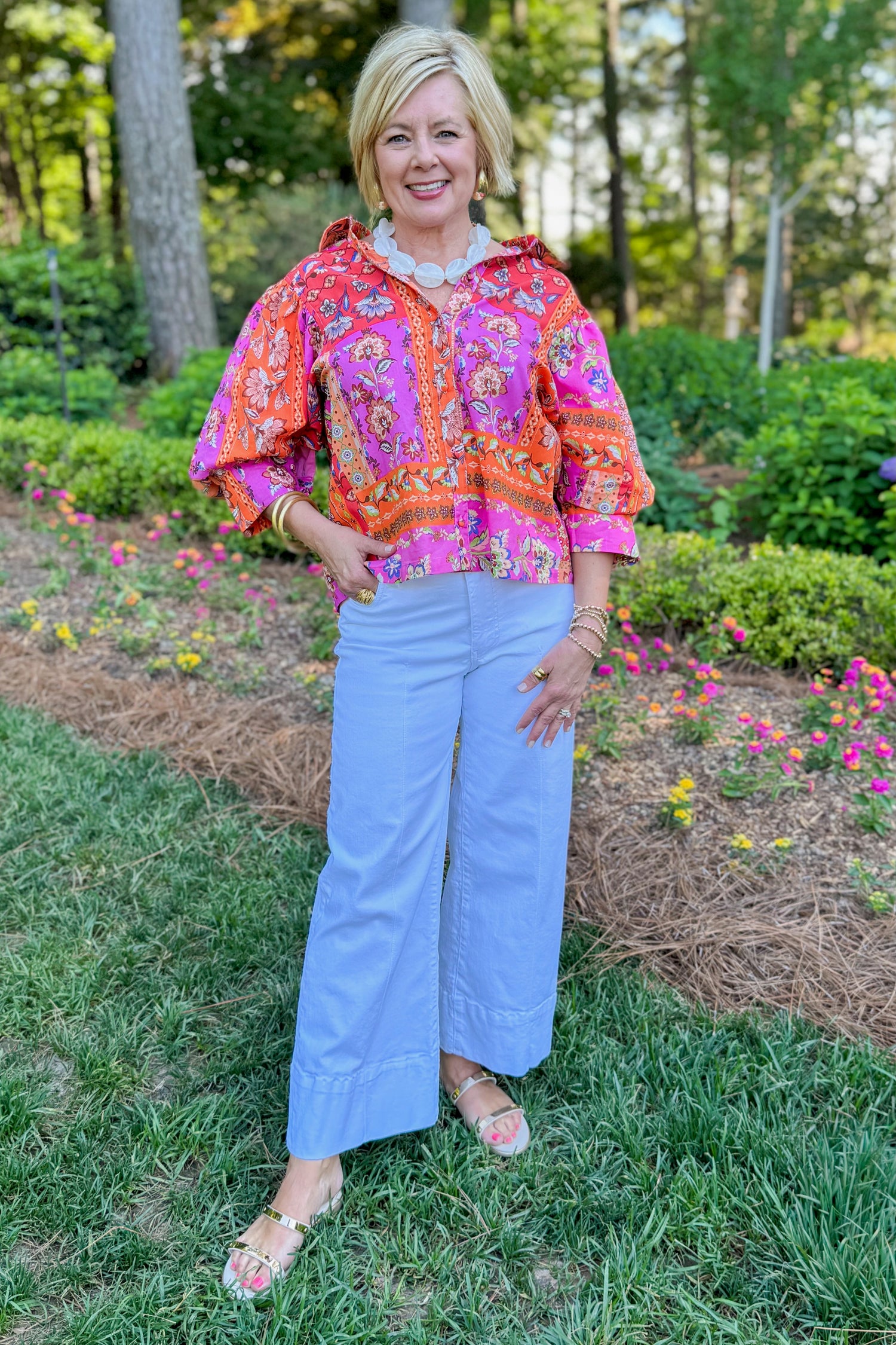 Front view of woman wearing Swagger Boutique’s Multi Floral Patchwork Top with jeans standing outside.