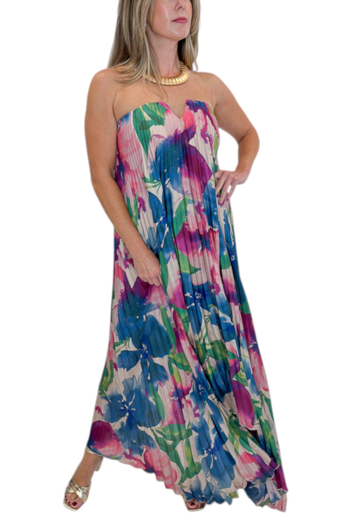 Front detail view of woman wearing Swagger Boutique’s Multi Floral Pleated Maxi Dress with heels against white studio background.