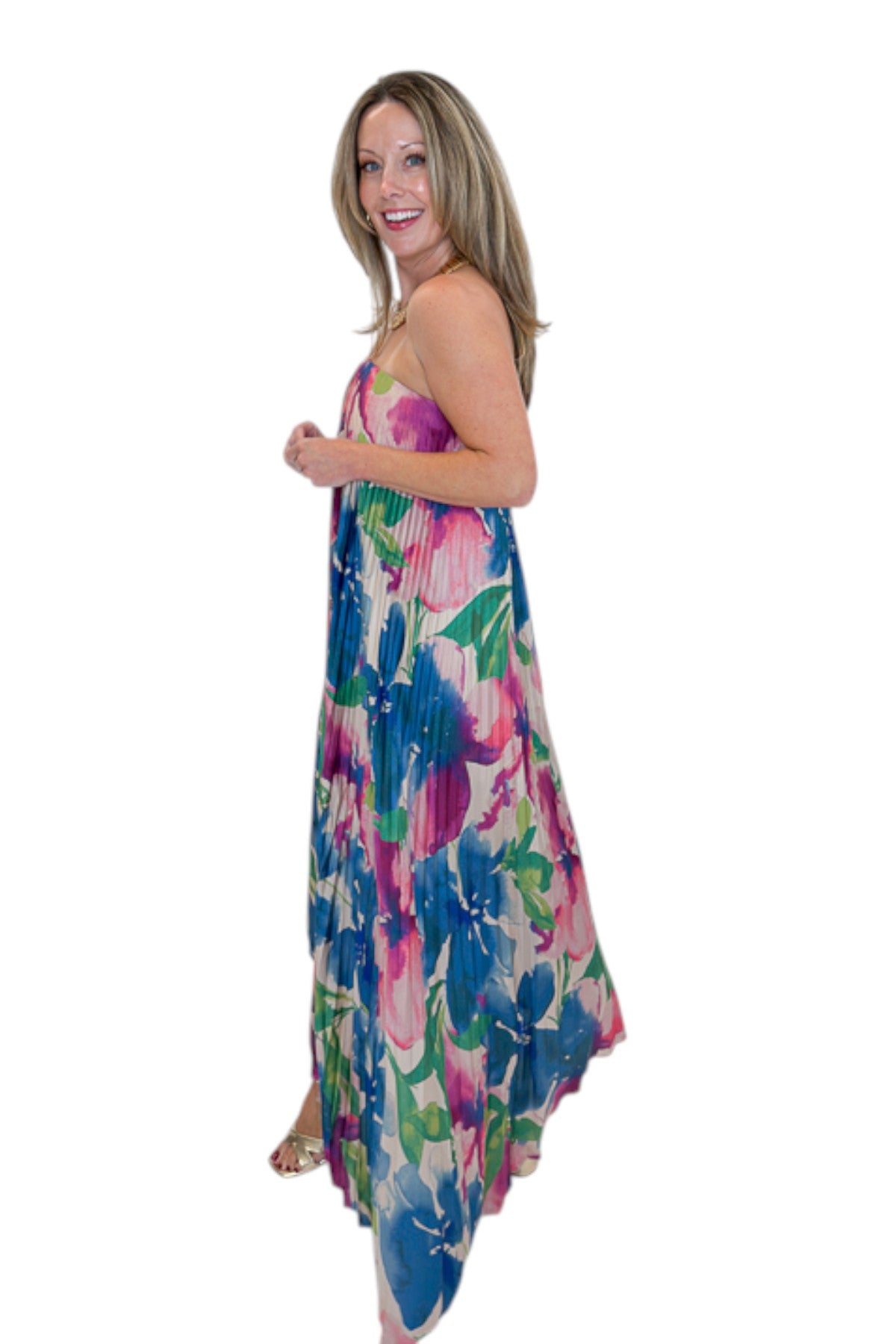Side view of woman wearing Swagger Boutique’s Multi Floral Pleated Maxi Dress with heels against white studio background.