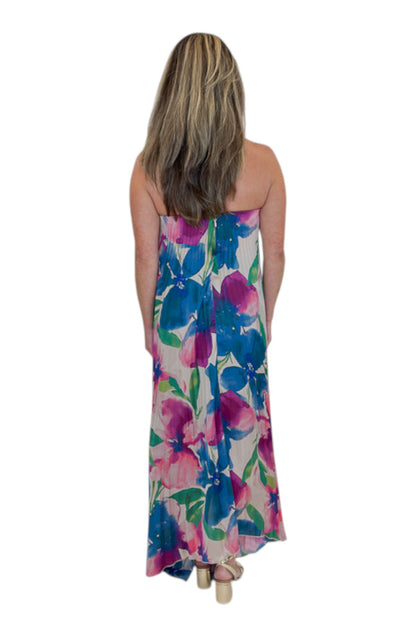 Back view of woman wearing Swagger Boutique’s Multi Floral Pleated Maxi Dress with heels against white studio background.