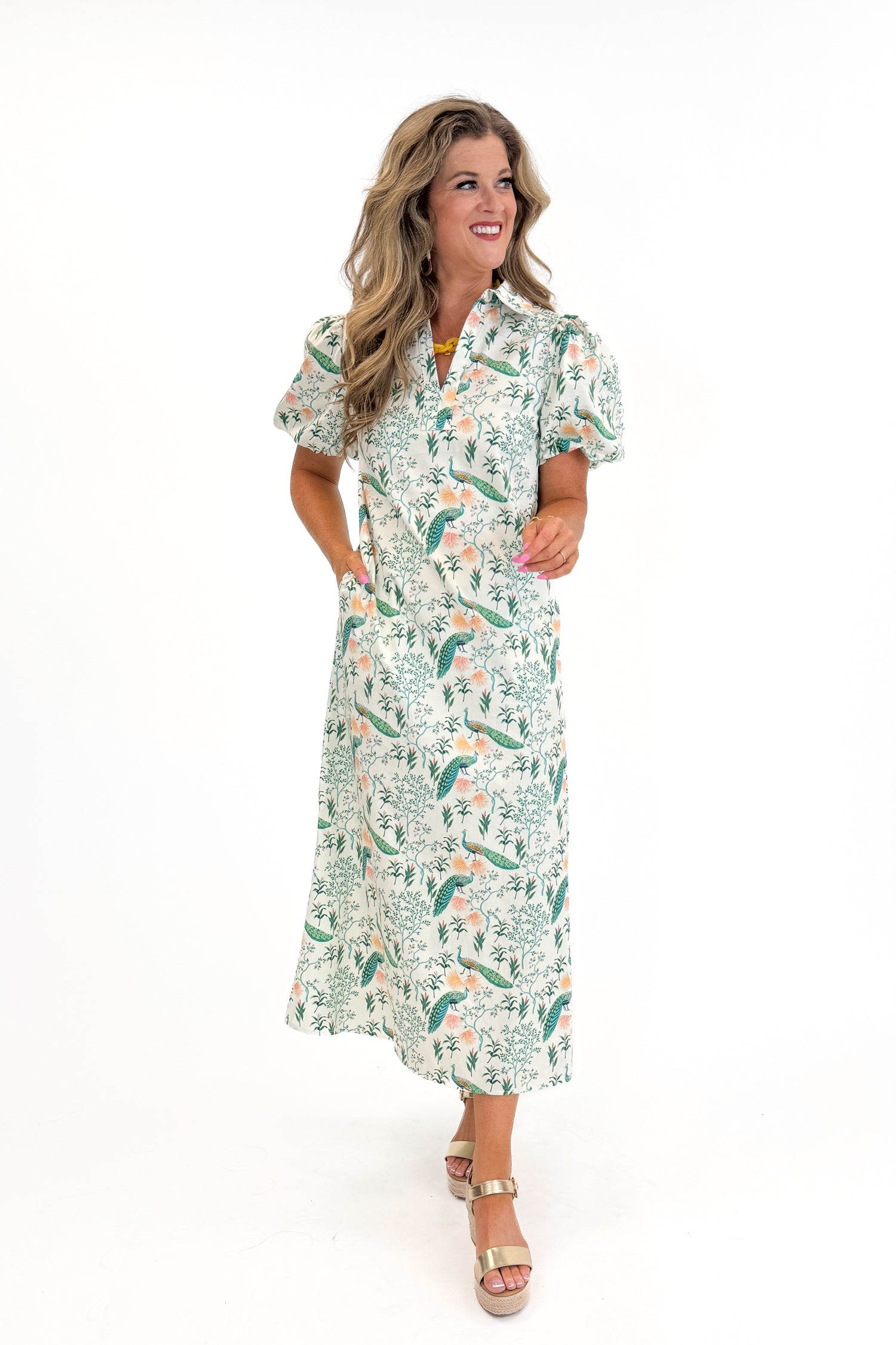 Front view of woman wearing Swagger Boutique’s Multi Peacock Print Maxi Dress with sandals against white studio background.