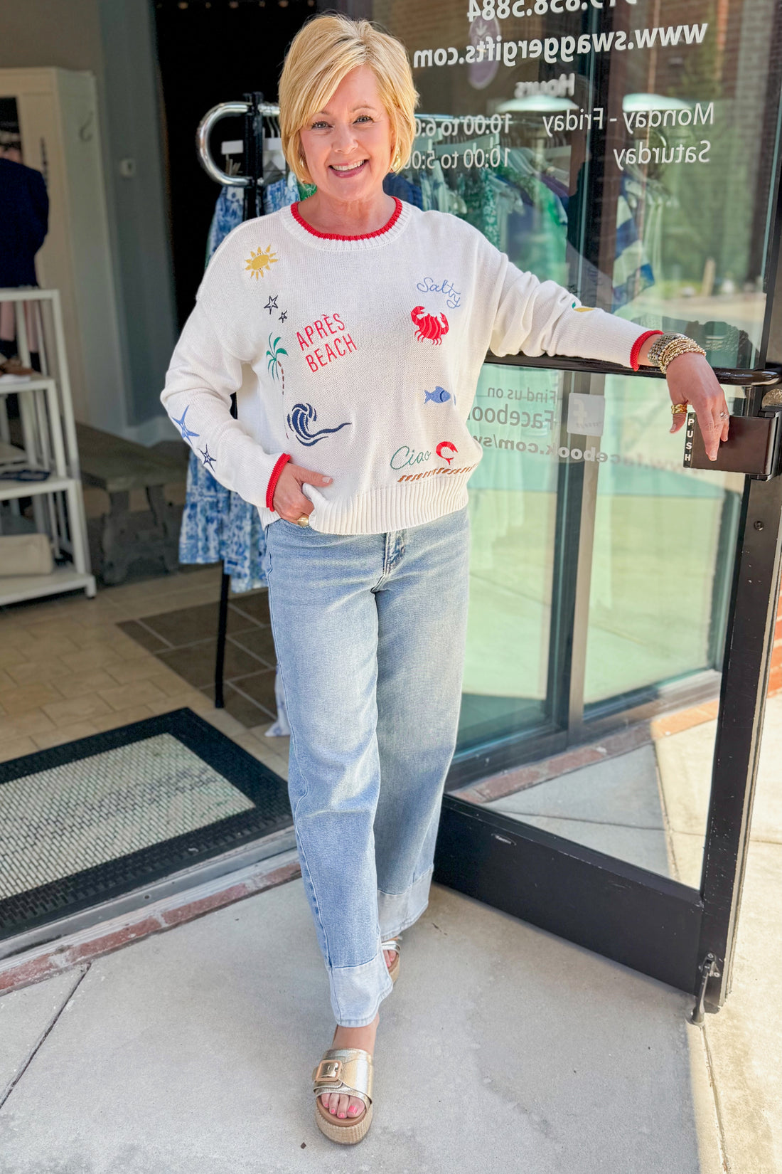 Front view of woman wearing Swagger Boutique’s Multi Seas The Day Sienna Sweater by Z Supply with jeans standing outside the store.