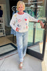 Front view of woman wearing Swagger Boutique’s Multi Seas The Day Sienna Sweater by Z Supply with jeans standing outside the store.