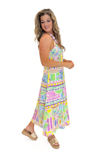 Side view of woman wearing Swagger Boutique’s Multi Tropical Print Maxi Dress with sandals against white studio background.