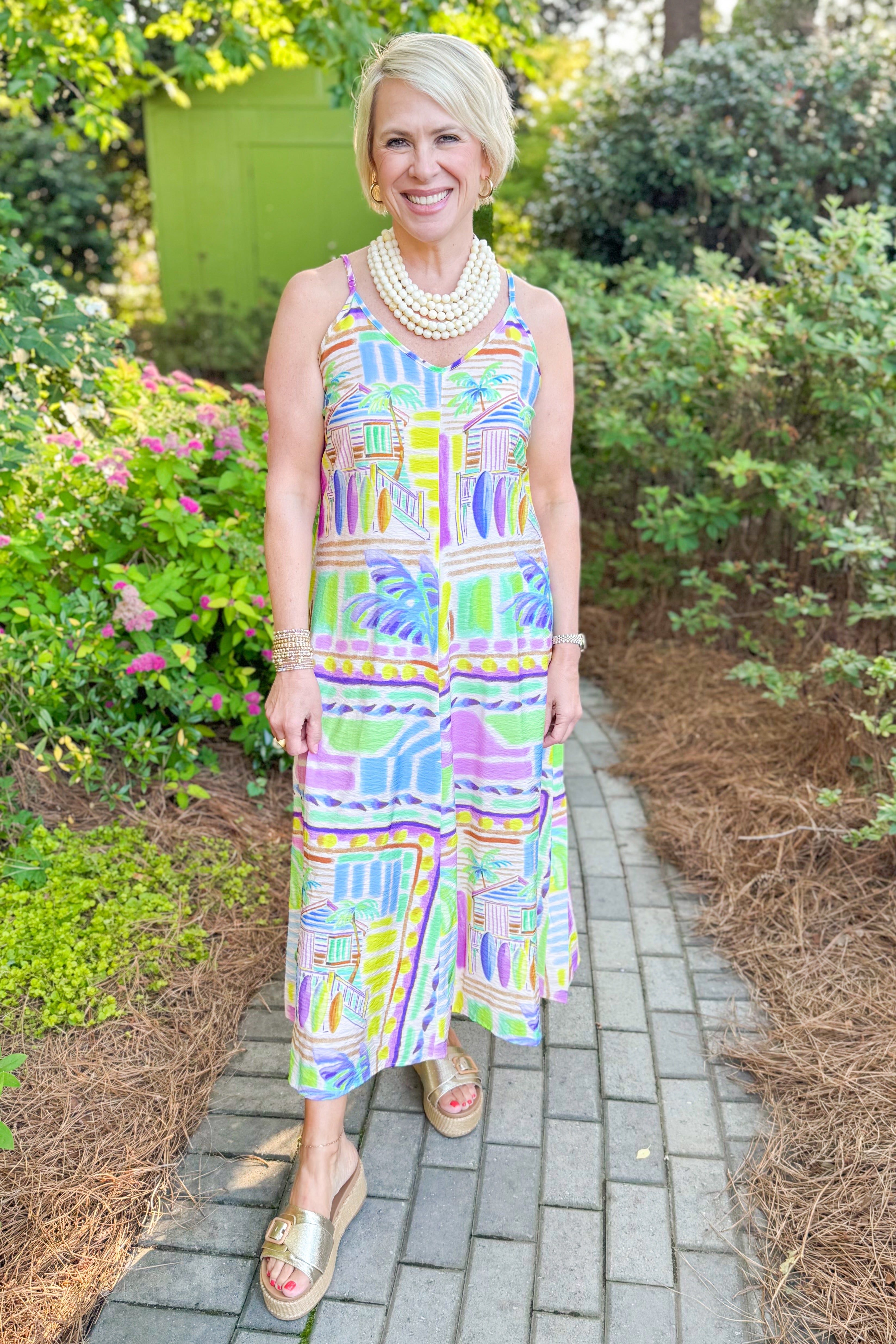 Front view of woman wearing Swagger Boutique’s Multi Tropical Print Maxi Dress with sandals walking outside.