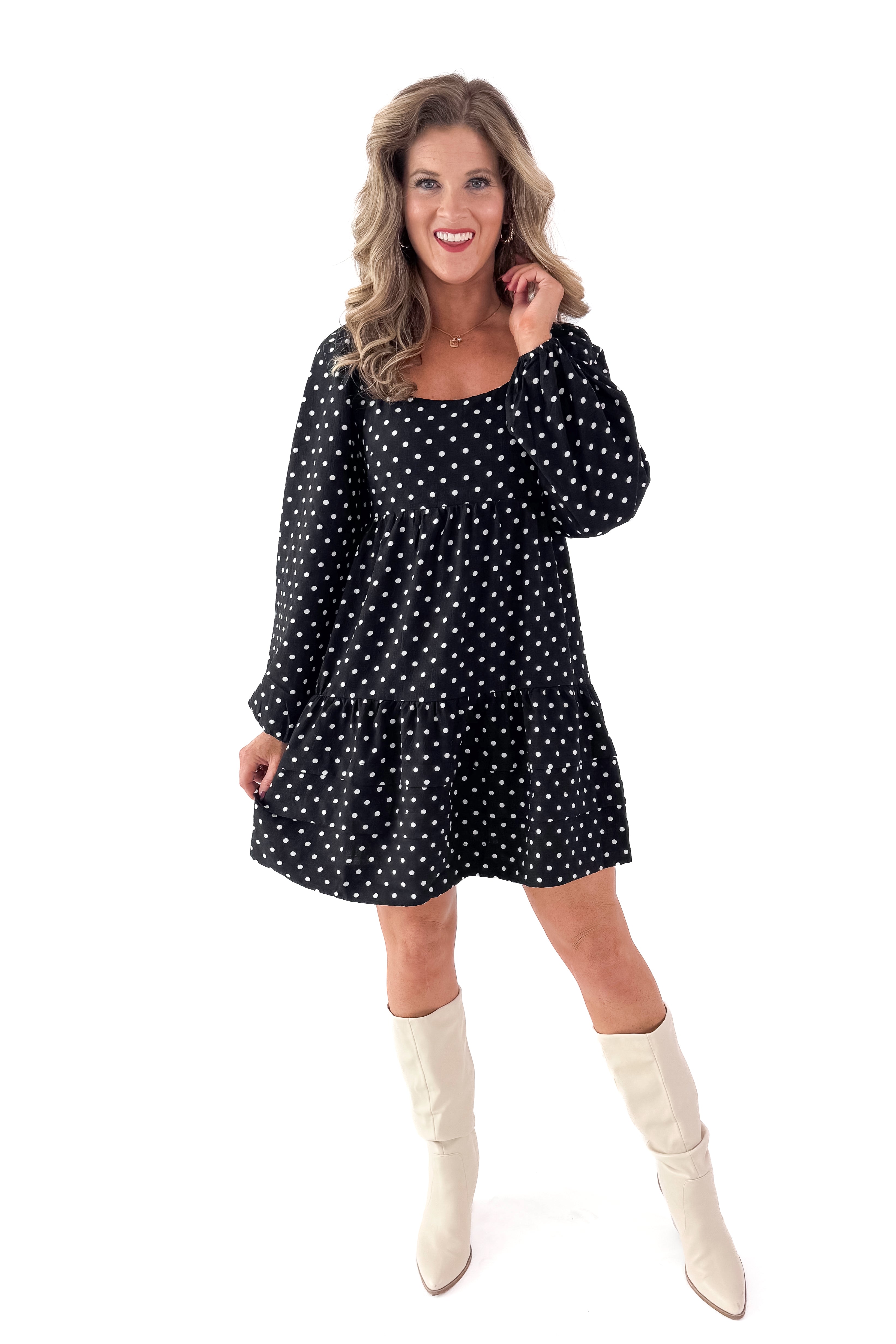 Front view of woman wearing polka dot dress and boots against white studio background.