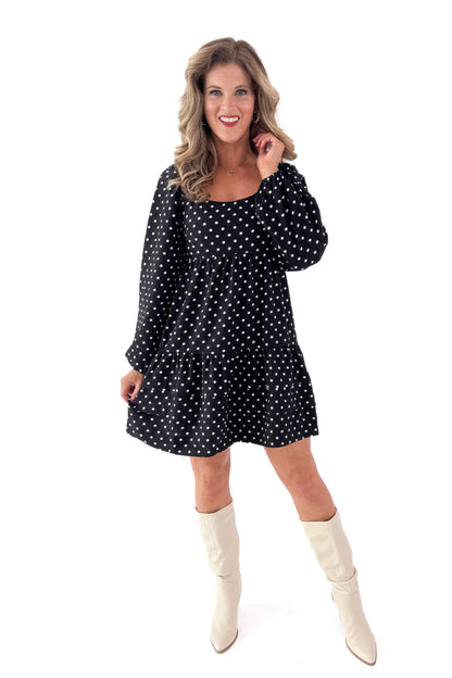 Front view of woman wearing polka dot dress and boots against white studio background.