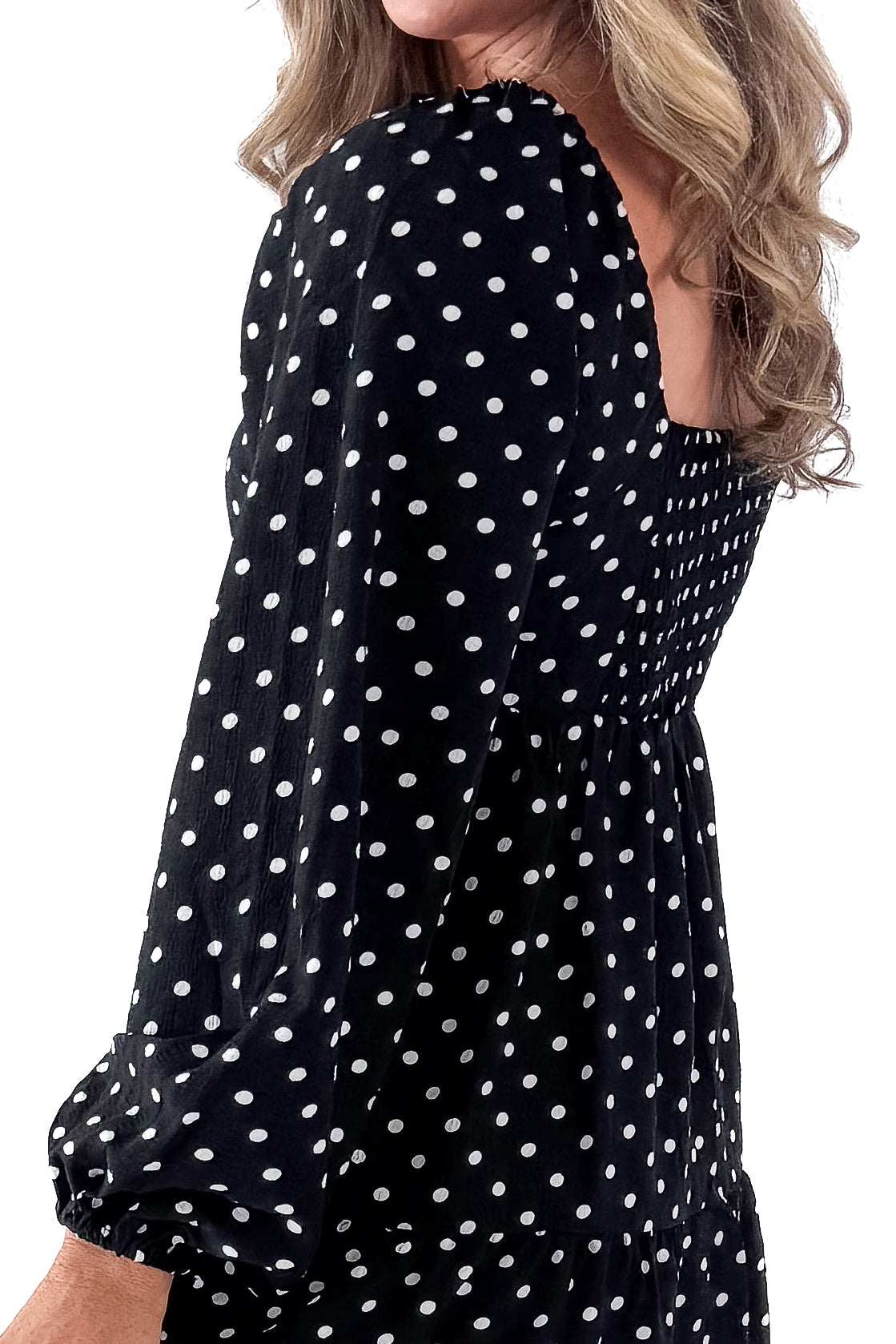 Side view of woman wearing polka dot dress and boots against white studio background.