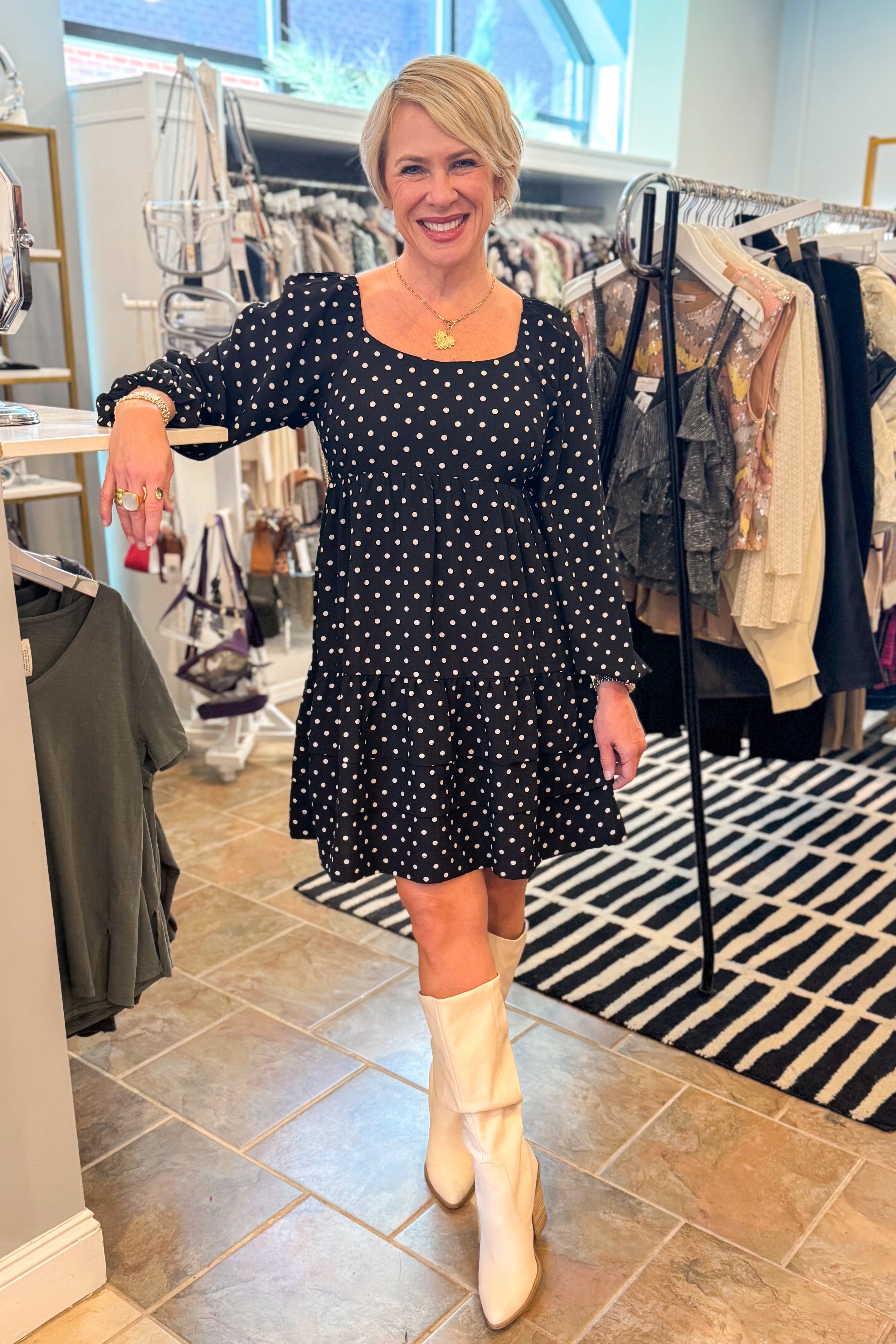 Front view of woman wearing polka dot dress and boots at a boutique.