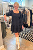 Front view of woman wearing polka dot dress and boots at a boutique.