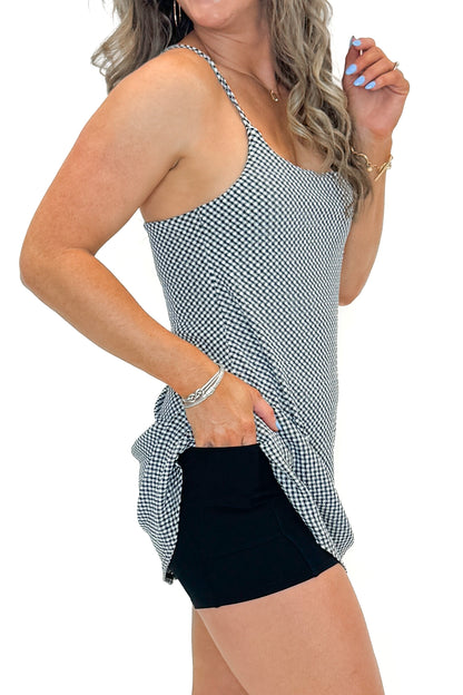 Side detail view of woman wearing Black &amp; White Checkered Tennis Dress with sneakers against white studio background.