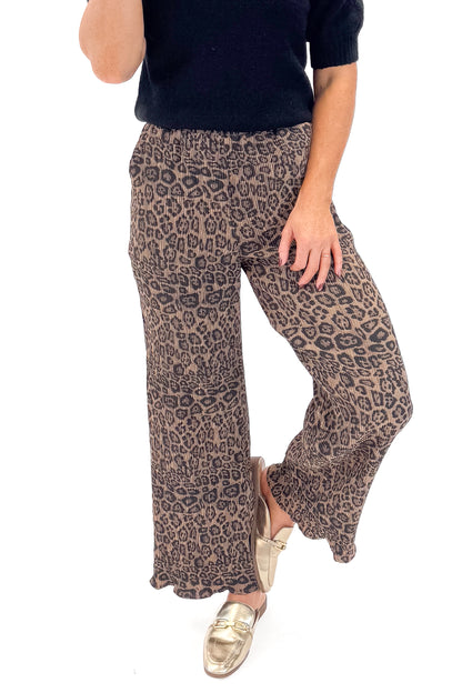 Front view of woman wearing Leopard Pleated Pants with sweater against white studio background.
