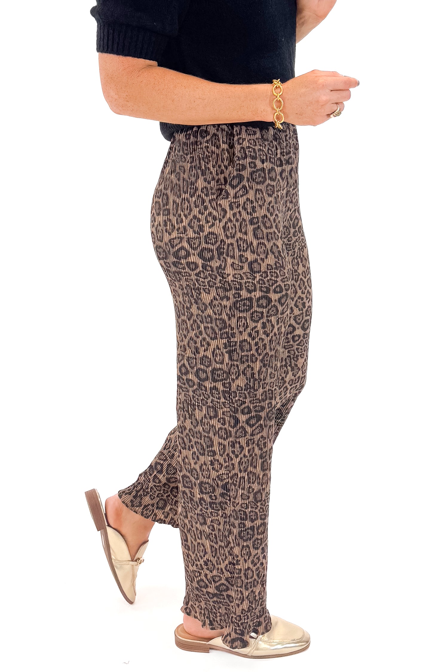 Side view of woman wearing Leopard Pleated Pants with sweater against white studio background.