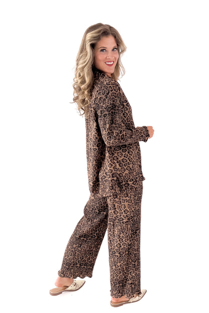 Side view of woman wearing Leopard Pleated Button Up Top with matching pants against white studio background.