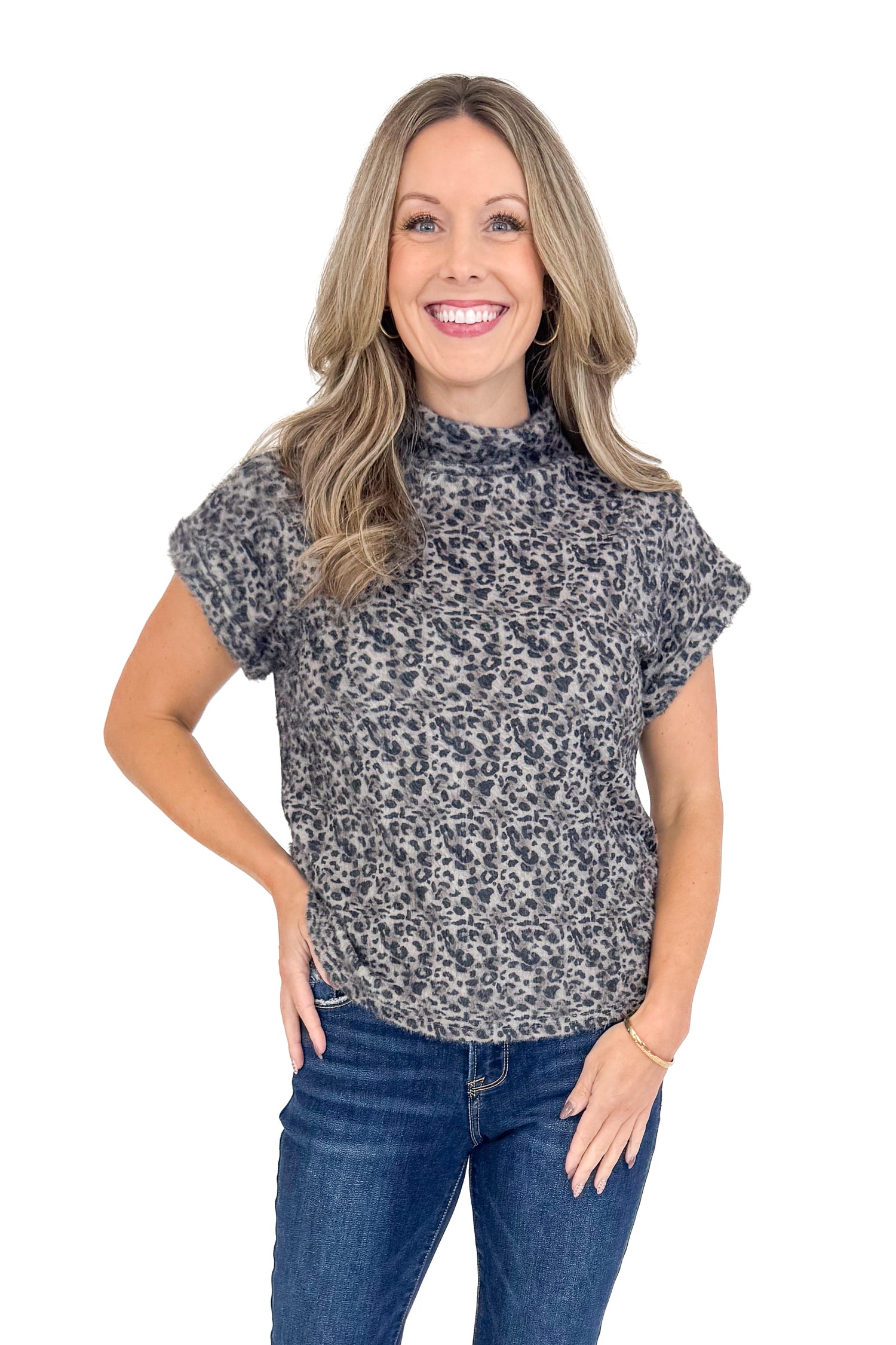 Front view of woman wearing Grey Leopard Short Sleeve Fuzzy Top and blue jeans. 
