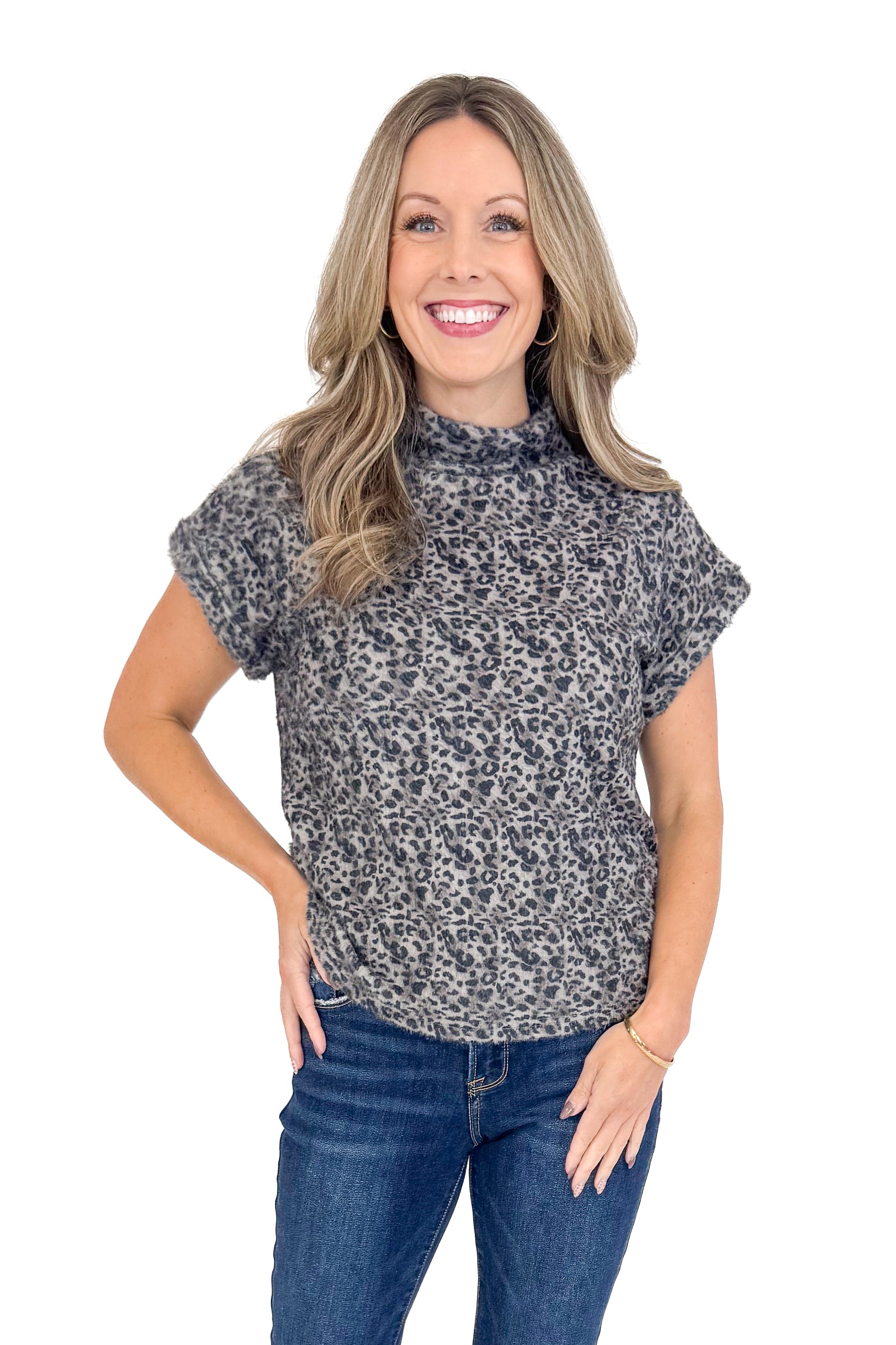 Front view of woman wearing Grey Leopard Short Sleeve Fuzzy Top and blue jeans. 