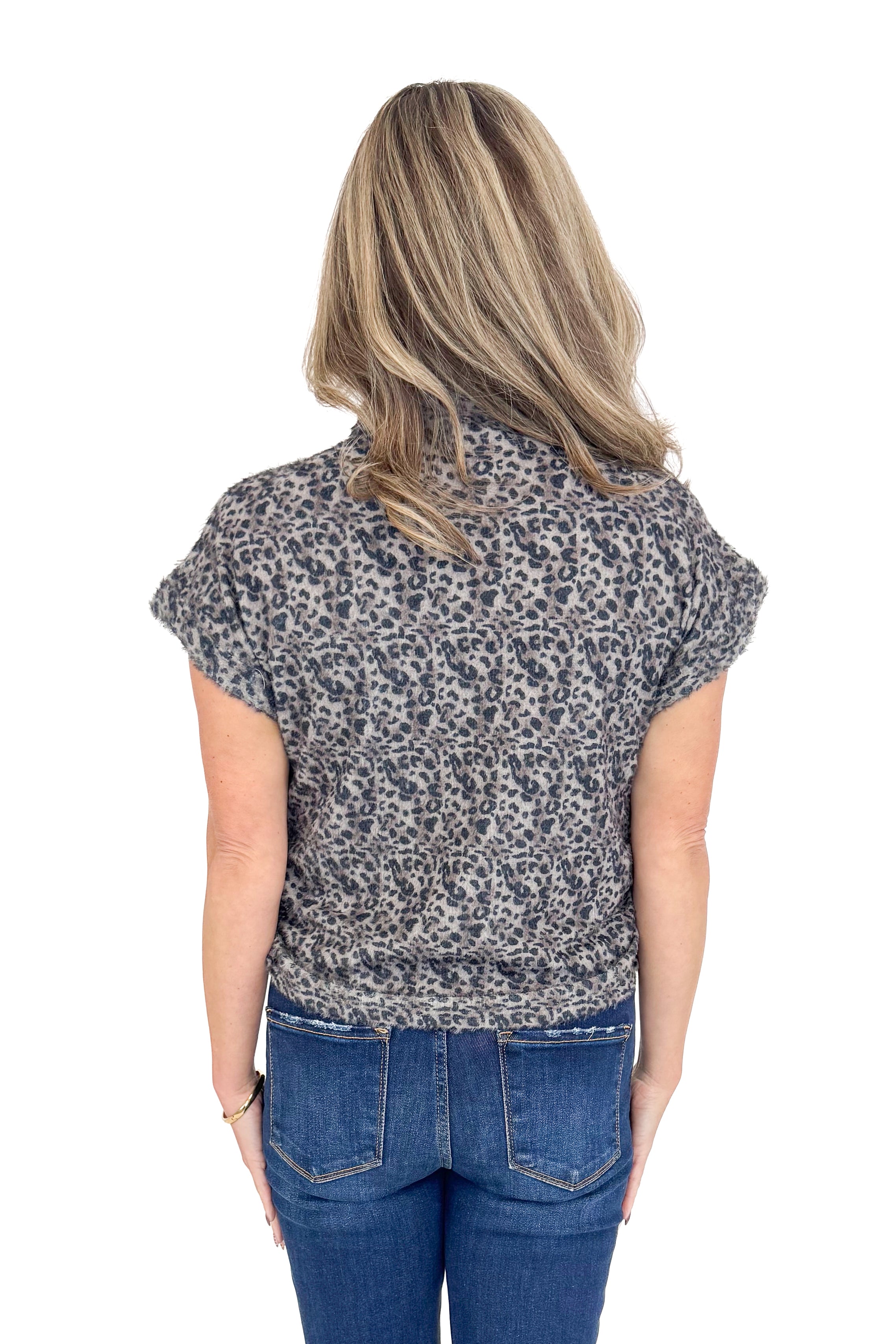 Back view of woman wearing Grey Leopard Short Sleeve Fuzzy Top and blue jeans. 