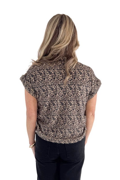 Back view of woman wearing Mocha Leopard Short Sleeve Fuzzy Top with jeans against white studio background.