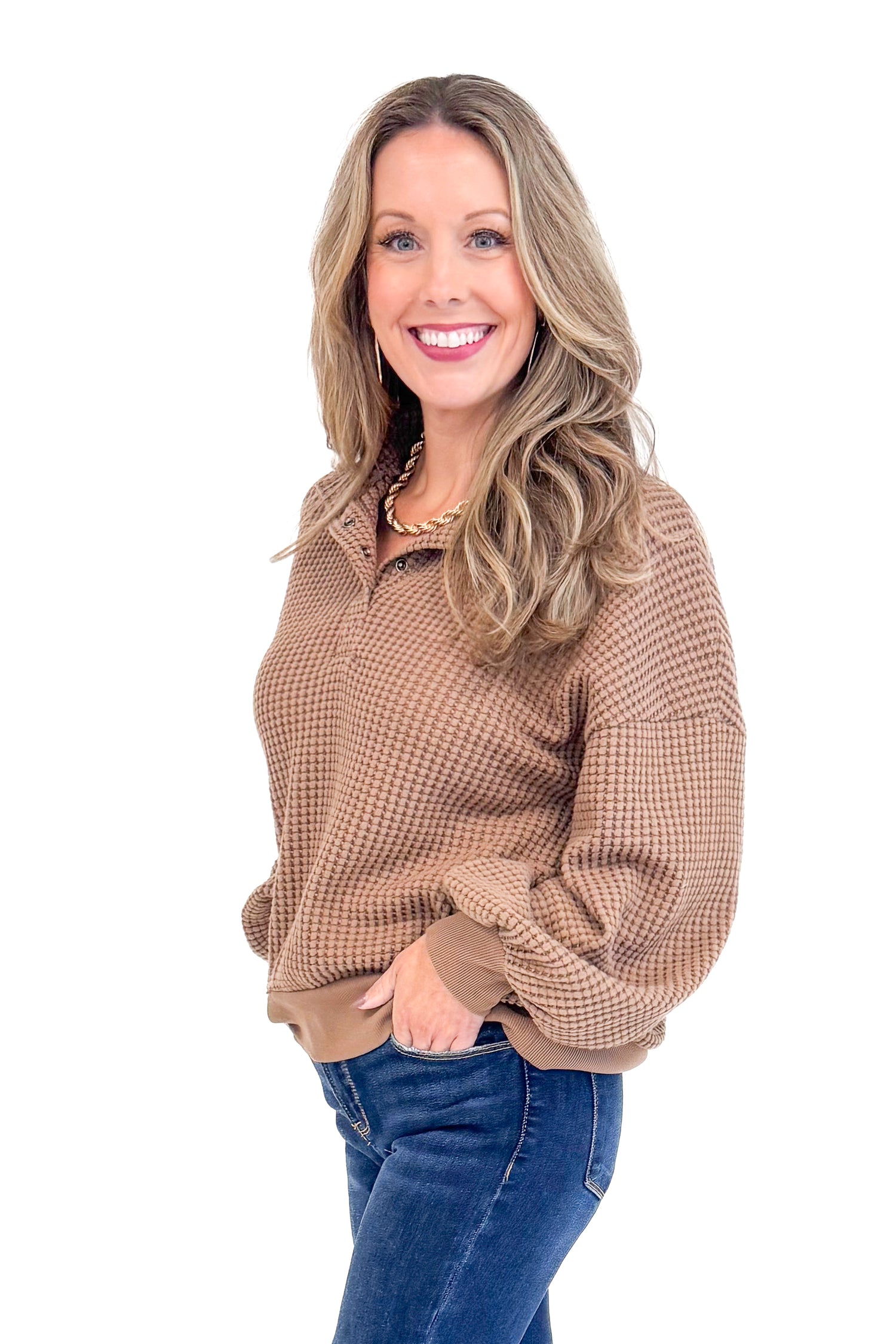 Side view of woman wearing Chocolate Waffle Knit Button Detail Top and jeans with a white background. 