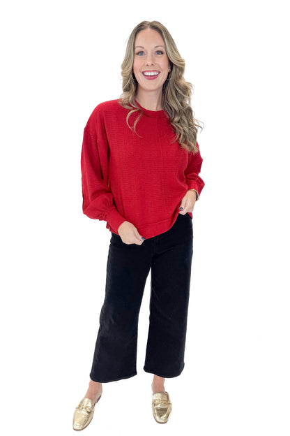 Front view of woman wearing Red Center Seam Textured Top with jeans against white studio background.