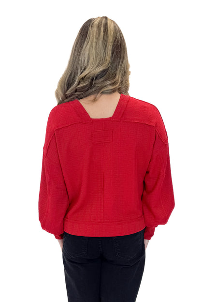 Back view of woman wearing Red Center Seam Textured Top with jeans against white studio background.