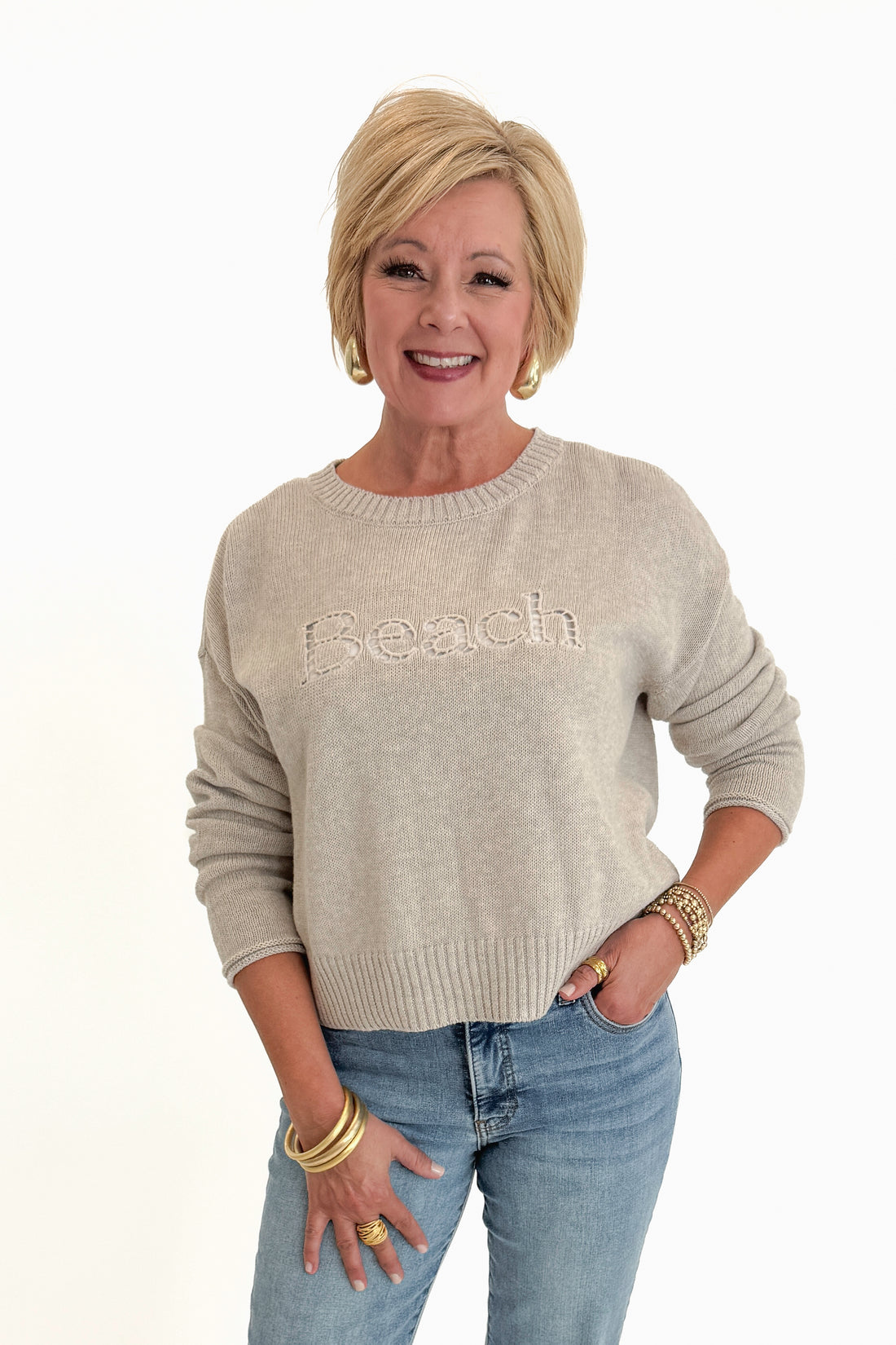 Front view of woman wearing Swagger Boutique’s Natural Heather Beach Embroidered Sweater by Z Supply with jeans against white studio background.