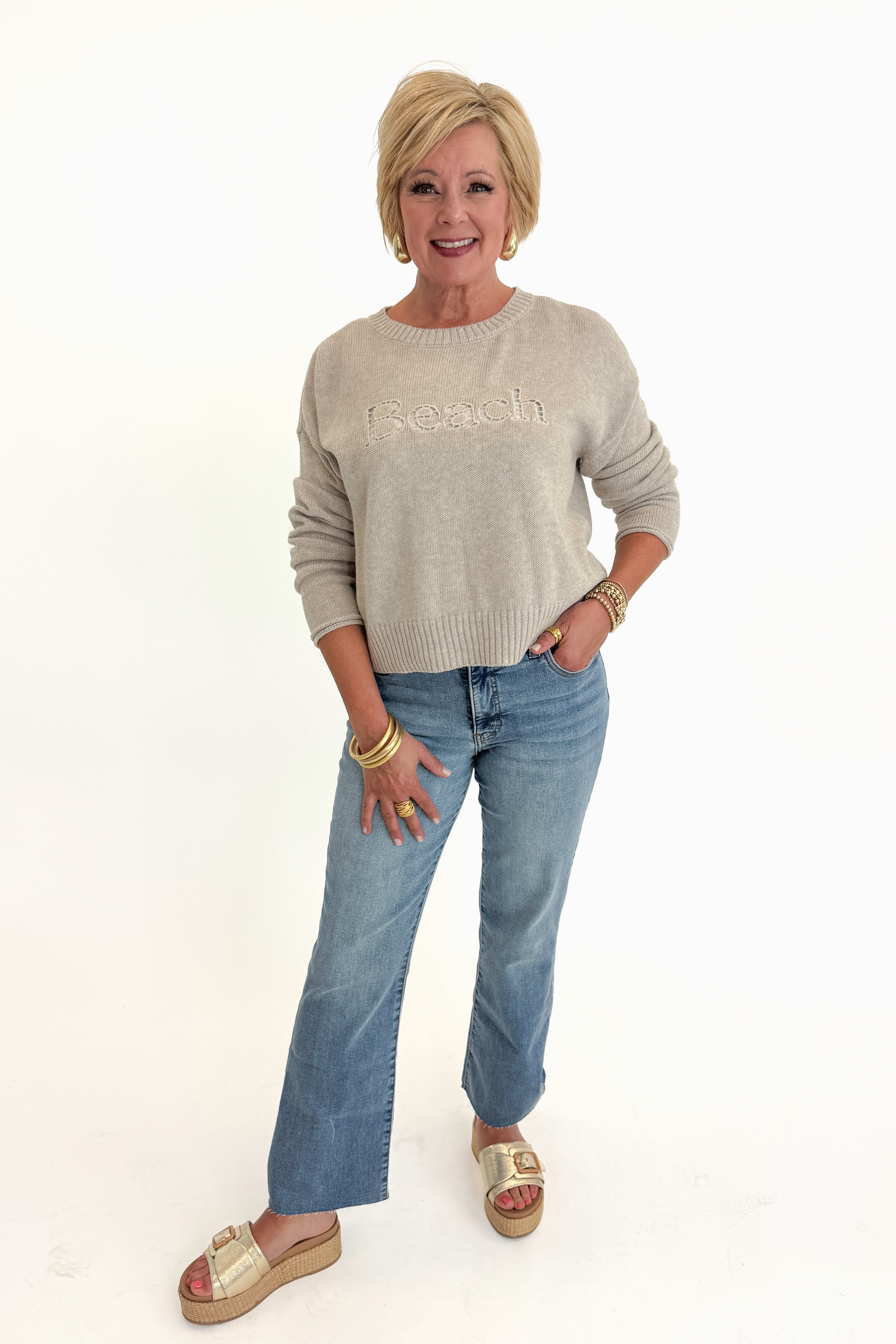 Front view of woman wearing Swagger Boutique’s Natural Heather Beach Embroidered Sweater by Z Supply with jeans against white studio background.