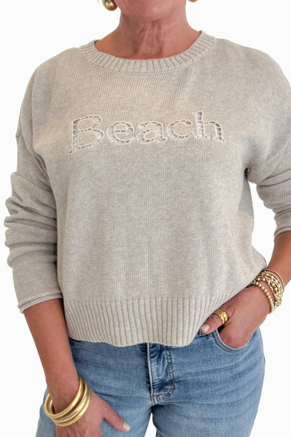 Front detail view of woman wearing Swagger Boutique’s Natural Heather Beach Embroidered Sweater by Z Supply with jeans against white studio background.