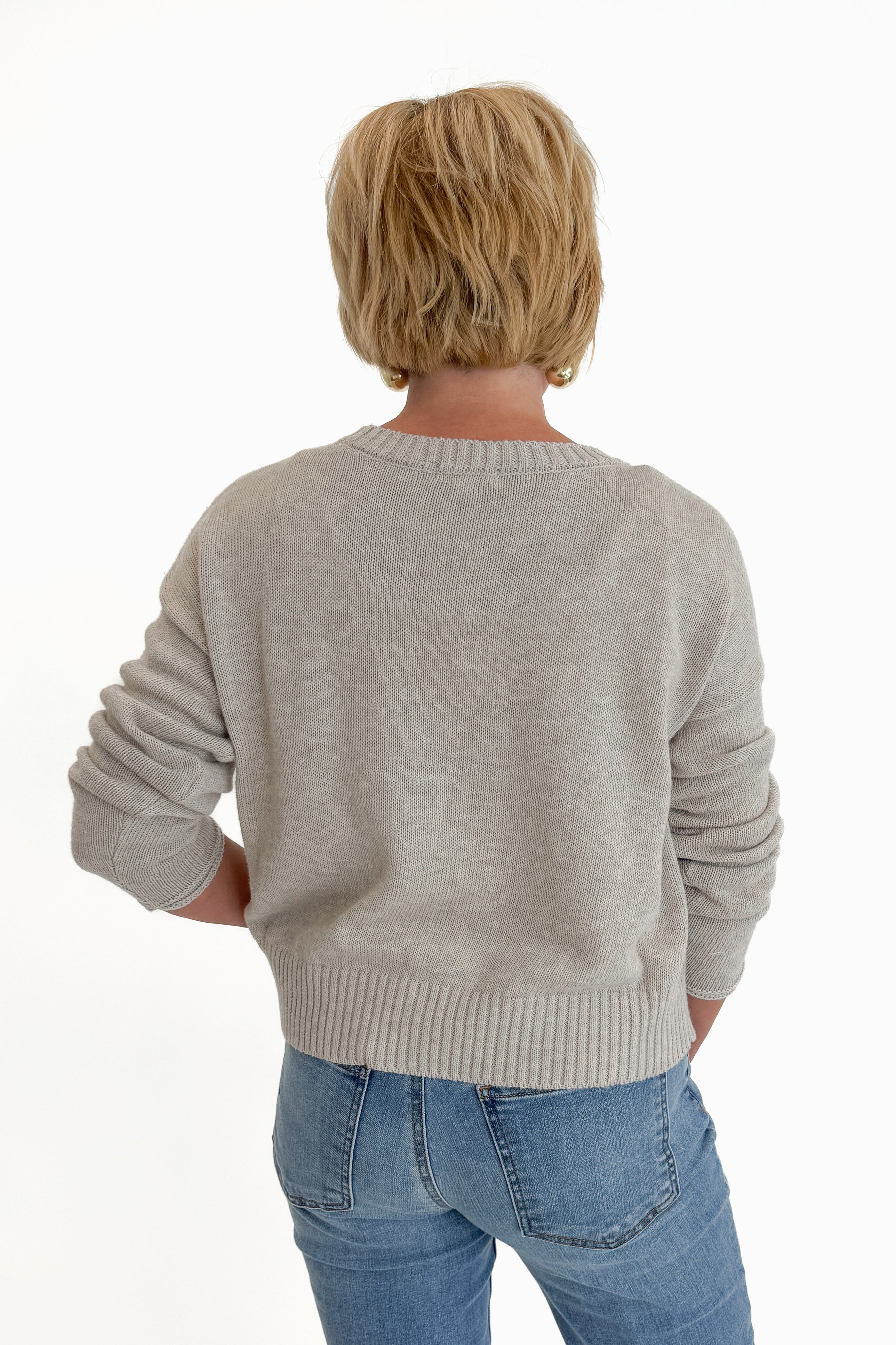Back view of woman wearing Swagger Boutique’s Natural Heather Beach Embroidered Sweater by Z Supply with jeans against white studio background.