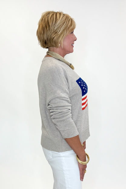 Side view of woman wearing Swagger Boutique’s Sienna Patriot Sweater In Natural Heather by Z Supply with jeans against white studio background. 