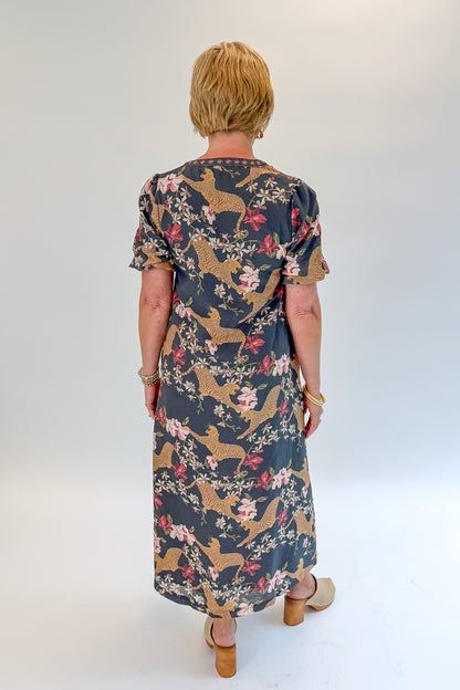 Back view of woman wearing Swagger Boutique’s Navy Animal Print Midi Dress with clogs against white studio background.