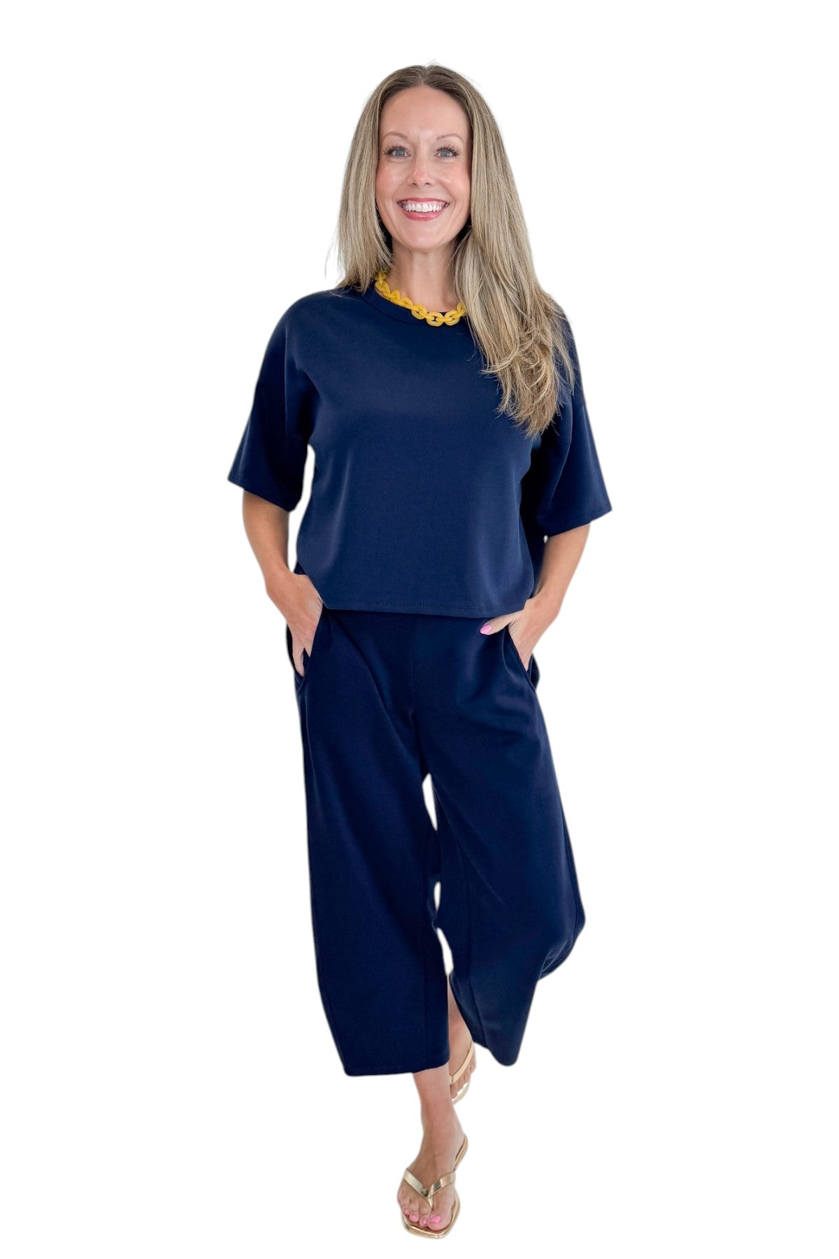 Front view of woman wearing Swagger Boutique’s Navy Barrel Lounge Pants with Navy Round Neck Short Sleeve Top against white studio background.