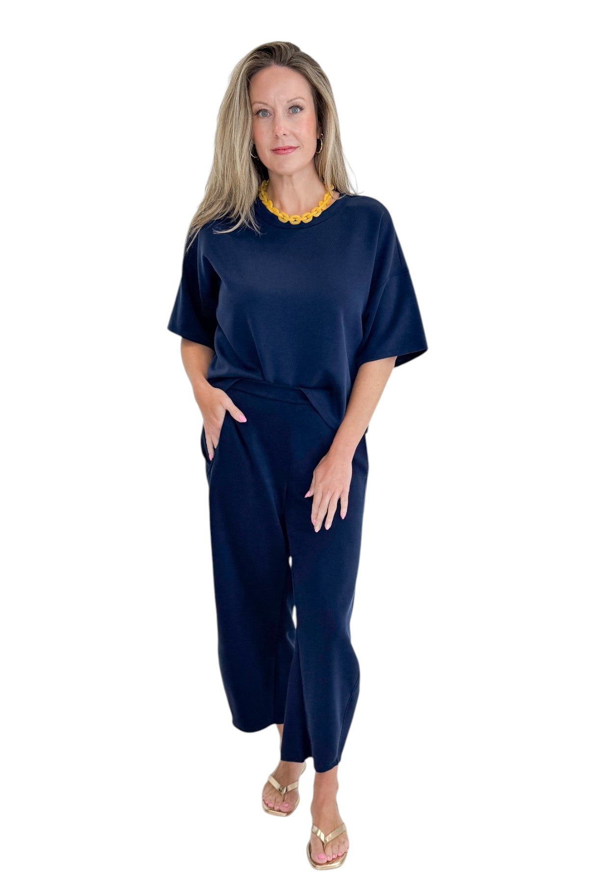 Front view of woman wearing Swagger Boutique’s Navy Barrel Lounge Pants with Navy Round Neck Short Sleeve Top against white studio background.
