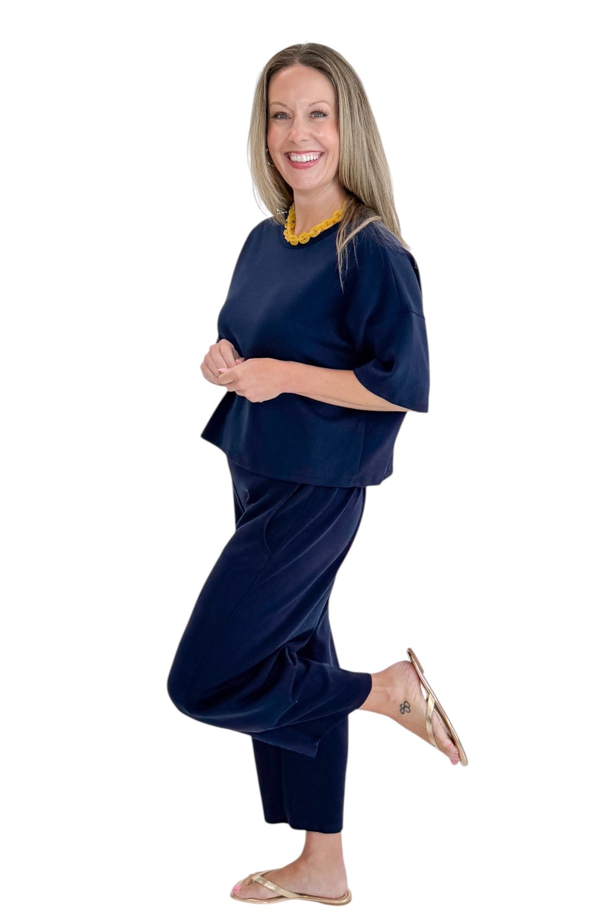 Side view of woman wearing Swagger Boutique’s Navy Barrel Lounge Pants with Navy Round Neck Short Sleeve Top against white studio background.